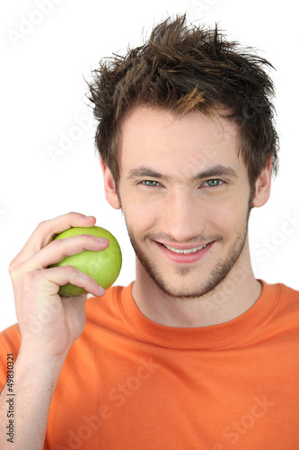 Photo: young man with orange shirt holding apple young man with orange shirt holding apple