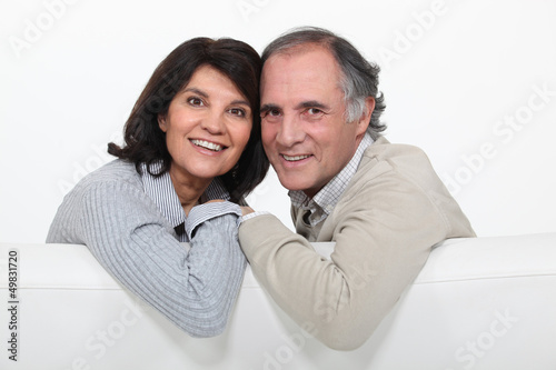 Photo: happy mature couple sitting on the couch happy mature couple sitting on the couch