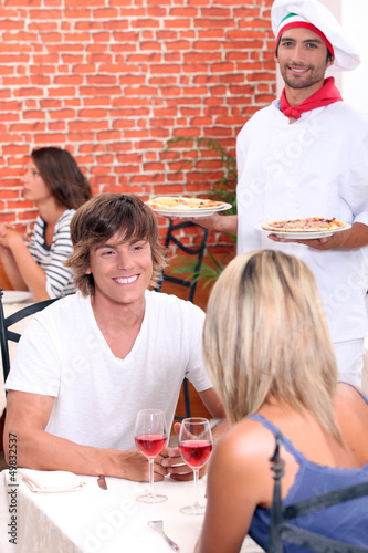 Photo: Young couple on a date in a pizzeria. Young couple on a date in a pizzeria.