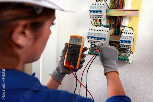 Photo: Female electrician checking a fusebox Female electrician checking a fusebox