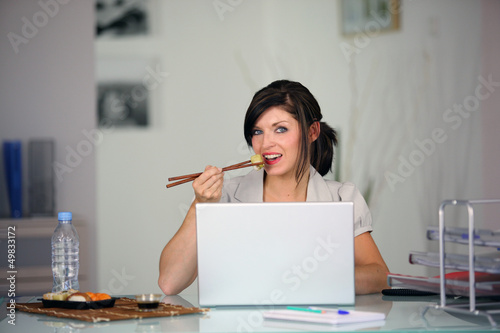 Photo: Woman eating in front of computer Woman eating in front of computer