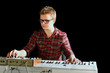 Young musician sits and plays electric organ