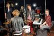 Group of young musicians in studio with mirror wall