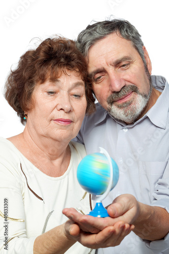 Photo: Elderly man and woman look at small globe Elderly man and woman look at small globe