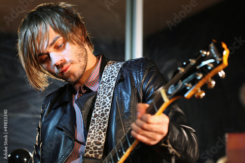 Photo: Guitarist in black leather jacket with electroguitar in studio Guitarist in black leather jacket with electroguitar in studio