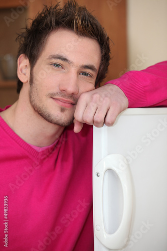 Photo: young man posing with arm on fridge door young man posing with arm on fridge door