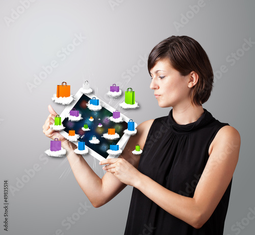 Photo: woman holding modern tablet with colorful shopping bags on cloud woman holding modern tablet with colorful shopping bags on cloud