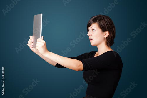 Photo: Young woman looking at modern tablet Young woman looking at modern tablet