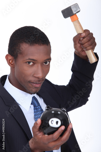 Photo: Man about to break open a piggy bank with a hammer Man about to break open a piggy bank with a hammer