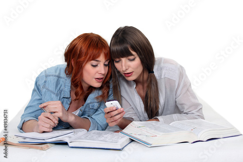 Photo: Two female students procrastinating. Two female students procrastinating.