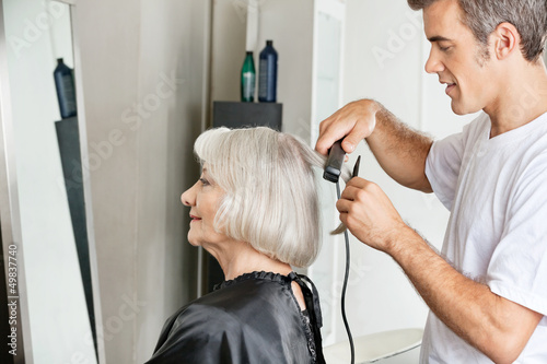 Photo: Hairstylist Straightening Customer's Hair Hairstylist Straightening Customer's Hair