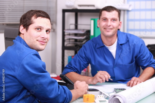 Photo: Two manual worker in the office checking stock levels Two manual worker in the office checking stock levels