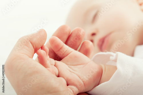 Photo: hand the sleeping baby in the hand of mother hand the sleeping baby in the hand of mother
