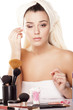 girl with towel on head fixes her makeup