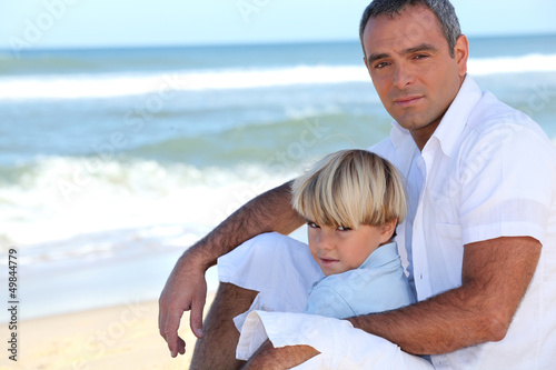 Photo: Father and son sitting on a beach Father and son sitting on a beach