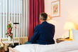 Älterer Mann sitzt auf dem Bett im Hotelzimmer