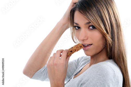 Photo: young woman eating a cereal bar young woman eating a cereal bar
