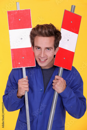 Photo: Man holding two metal road signs Man holding two metal road signs