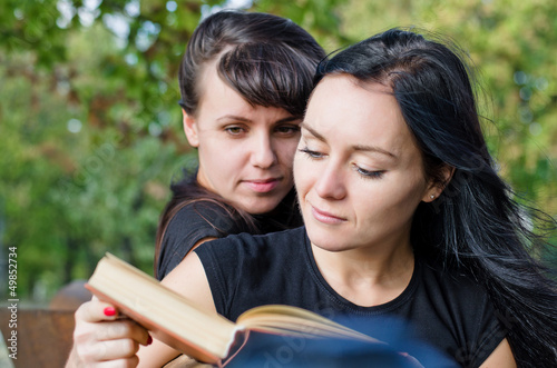 Photo: Two women reading a book together Two women reading a book together