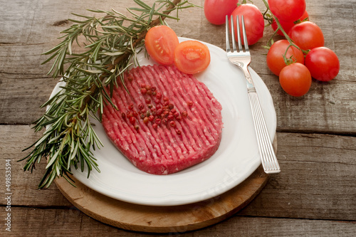 Photo: raw hamburger with tomato, herbs and pink pepper raw hamburger with tomato, herbs and pink pepper