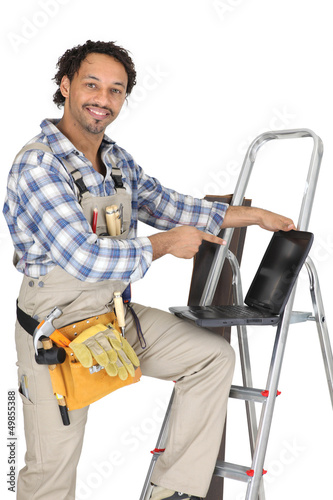 Photo: Handyman stood with ladder and pointing at laptop Handyman stood with ladder and pointing at laptop