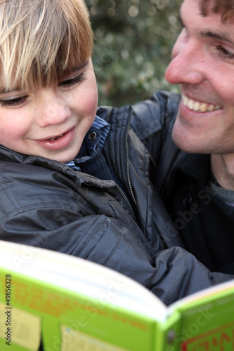 Photo: Father and son reading book outdoors Father and son reading book outdoors