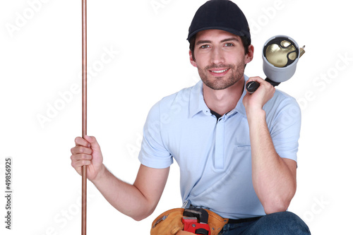 Photo: Tradesman holding a copper tube and a blowtorch Tradesman holding a copper tube and a blowtorch