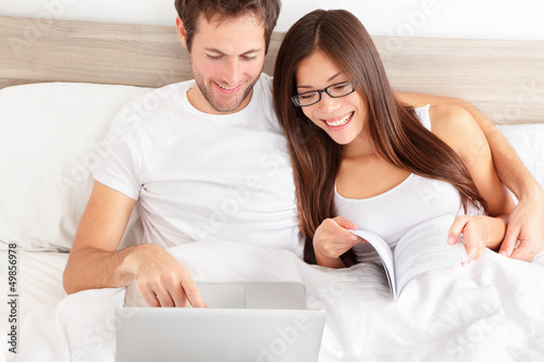 Photo: Happy affectionate couple laughing at their laptop Happy affectionate couple laughing at their laptop