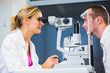 Optometry concept - handsome young man having his eyes examined