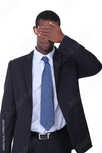 Photo: Man in a business suit with his hand covering his eyes Man in a business suit with his hand covering his eyes