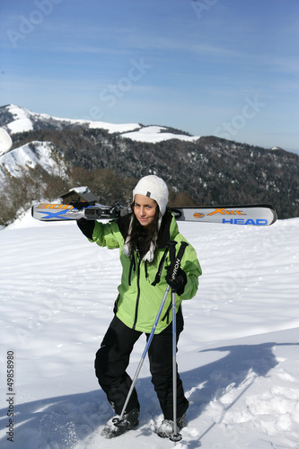 Photo: Young woman carrying her skis Young woman carrying her skis