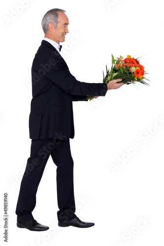 Photo: Man dressed in tuxedo holding bunch of lowers Man dressed in tuxedo holding bunch of lowers