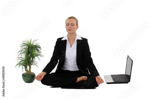 Photo: Businesswoman meditating next to her laptop Businesswoman meditating next to her laptop