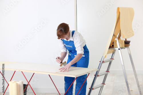 Photo: Woman putting up wallpaper Woman putting up wallpaper