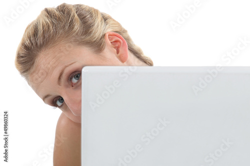 Photo: Woman peeking out from behind her laptop Woman peeking out from behind her laptop