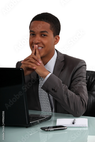 Photo: Happy black businessman sat at his desk Happy black businessman sat at his desk