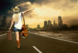 Young woman with guitar on the road and her vintage baggage