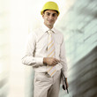Photo: Young architect wearing a protective helmet standing on the buil Young architect wearing a protective helmet standing on the buil