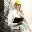 Photo: Young architect wearing a protective helmet standing on the buil Young architect wearing a protective helmet standing on the buil