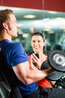 Trainer und Mann mit Hanteln im Fitnessstudio