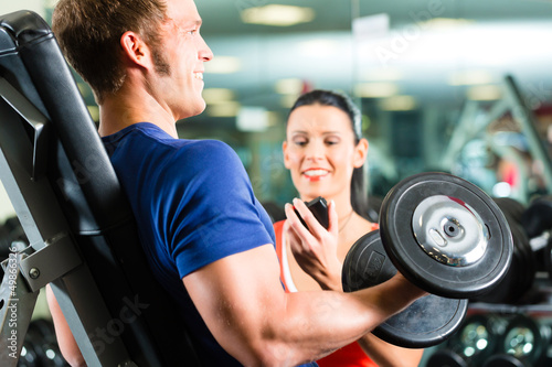 Photo: Trainer und Mann mit Hanteln im Fitnessstudio Trainer und Mann mit Hanteln im Fitnessstudio