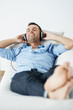 Cheerful man wearing headphones lying on the sofa