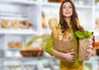 Woman in market  holding a grocery bag full of bread 
