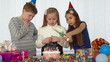 children blowing candles on birthday cake