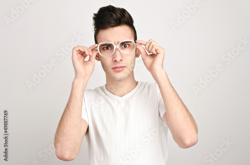 Photo: Confused, disturbed, upset.Young man with glasses frowning. Confused, disturbed, upset.Young man with glasses frowning.