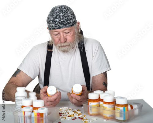 Photo: Senior holding prescription bottles with pills on table Senior holding prescription bottles with pills on table