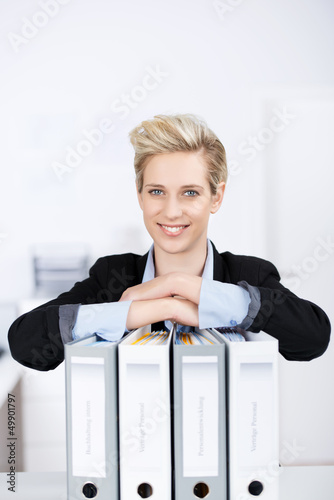 Photo: frau im büro stützt sich auf aktenordner frau im büro stützt sich auf aktenordner