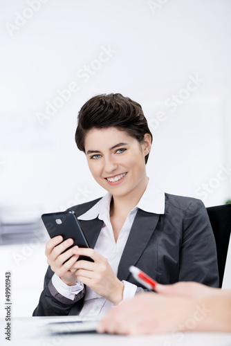 Photo: frau benutzt handy in einer besprechung frau benutzt handy in einer besprechung