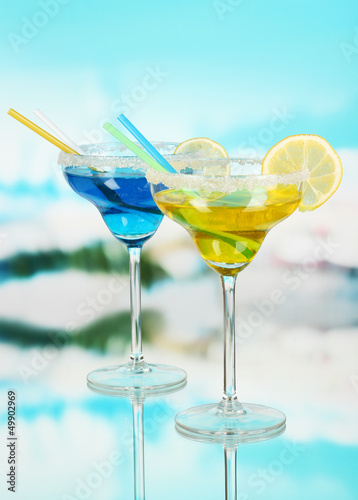 Photo: Yellow and blue cocktails in glasses on blue natural background Yellow and blue cocktails in glasses on blue natural background