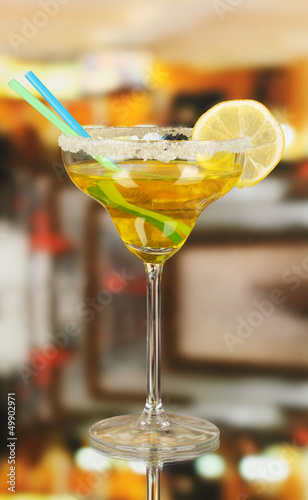 Photo: Yellow cocktail in glass on room background Yellow cocktail in glass on room background